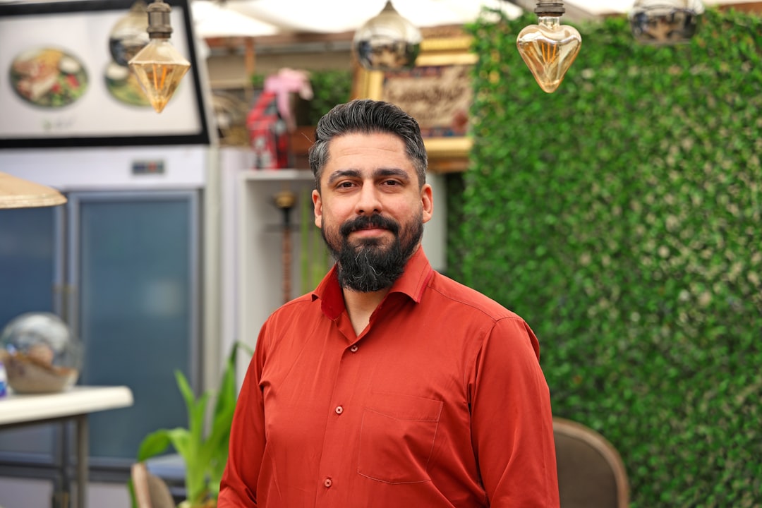 Man with beard in a red shirt smiling indoors