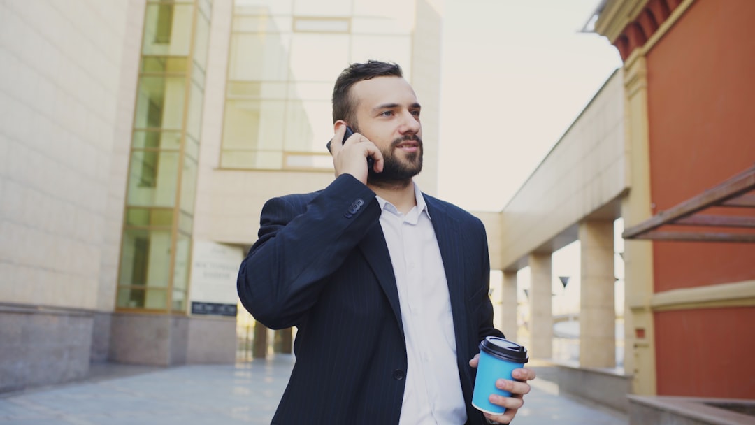 Man in suit talking on phone with coffee cup.