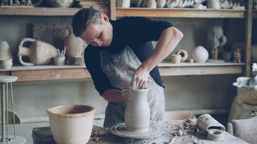 A potter works on a vase in a pottery studio.