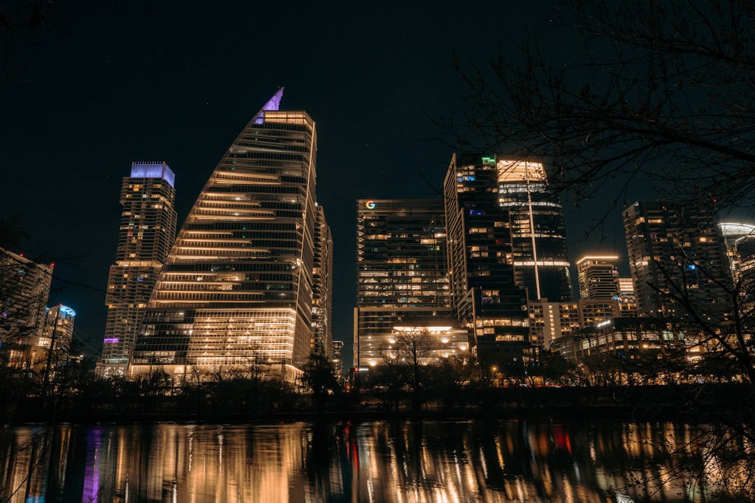 Modern skyscrapers illuminated at night with water reflection.