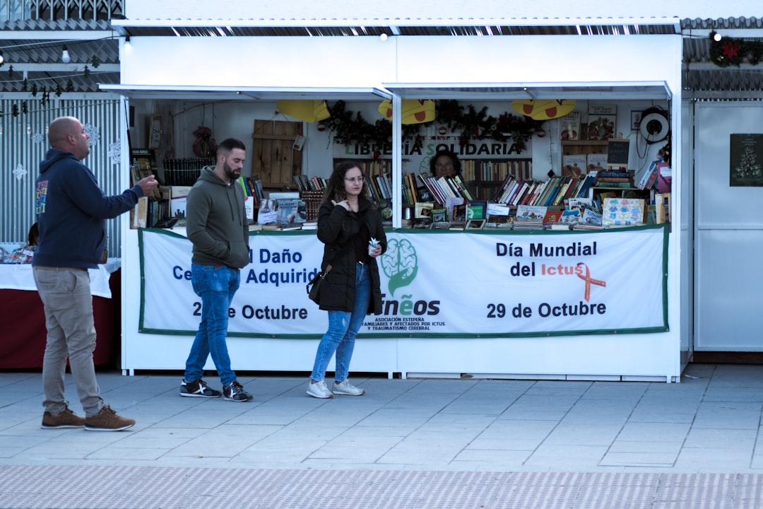 People browsing a market stall with books and crafts.