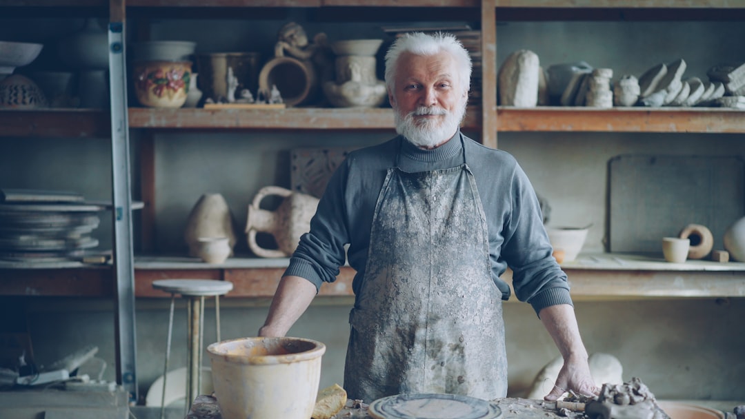 A potter smiles proudly in his workshop.