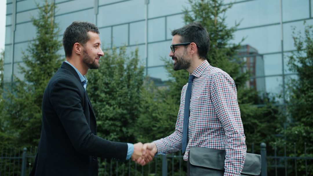 Two businessmen shaking hands outside an office building.