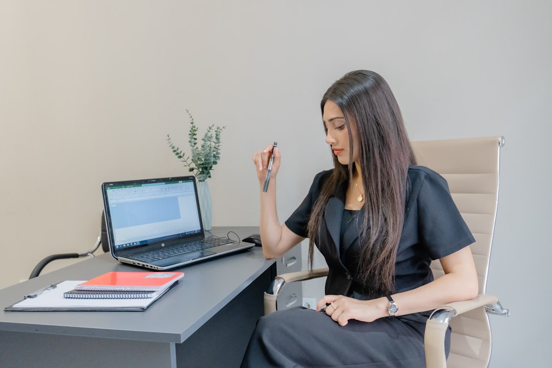 A woman in a black suit works at a desk.